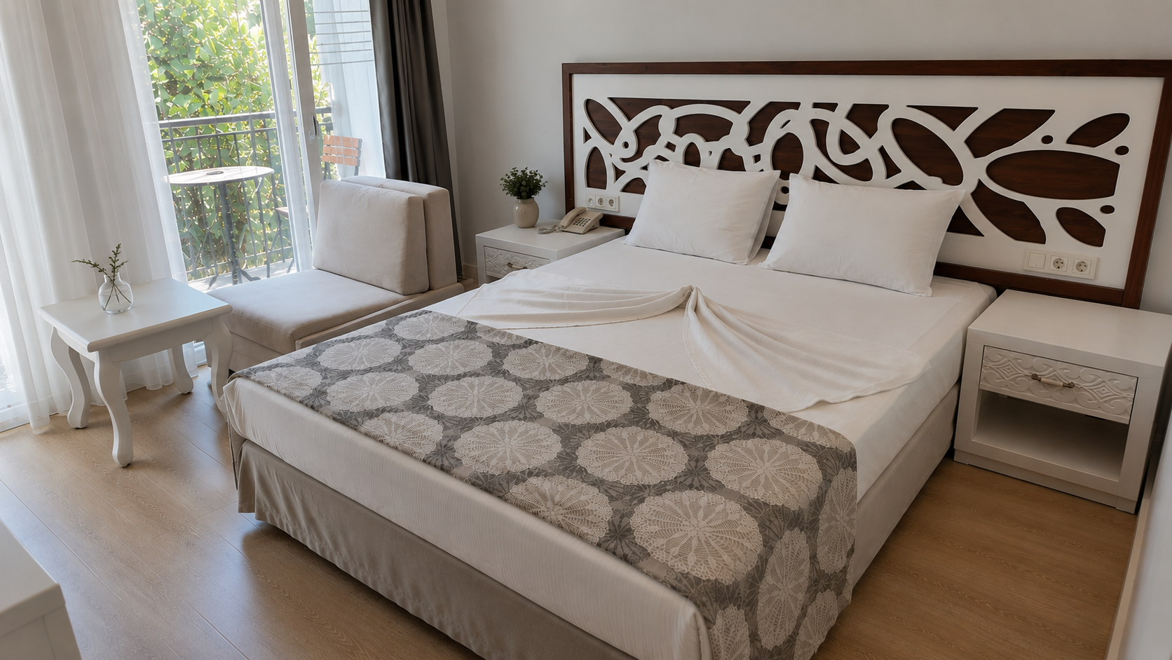 Standard room bed with carved wooden headboard and balcony beyond